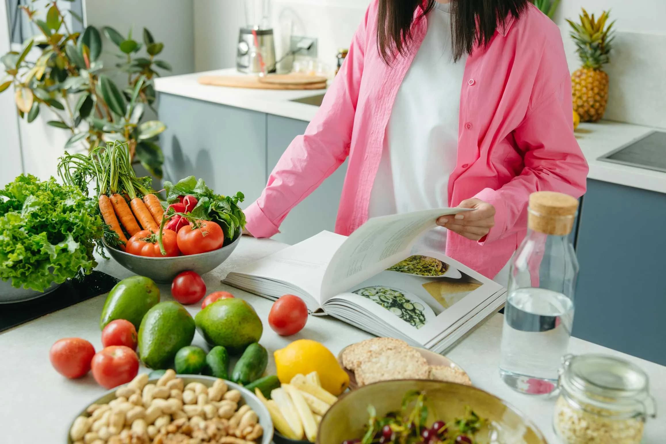 A person cooking with an open cookbook in a kitchen.